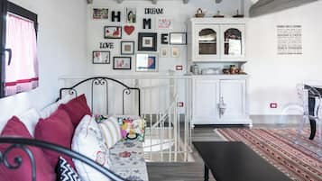 A cozy room with a bed, a bench, a dining table, and a kitchen area.