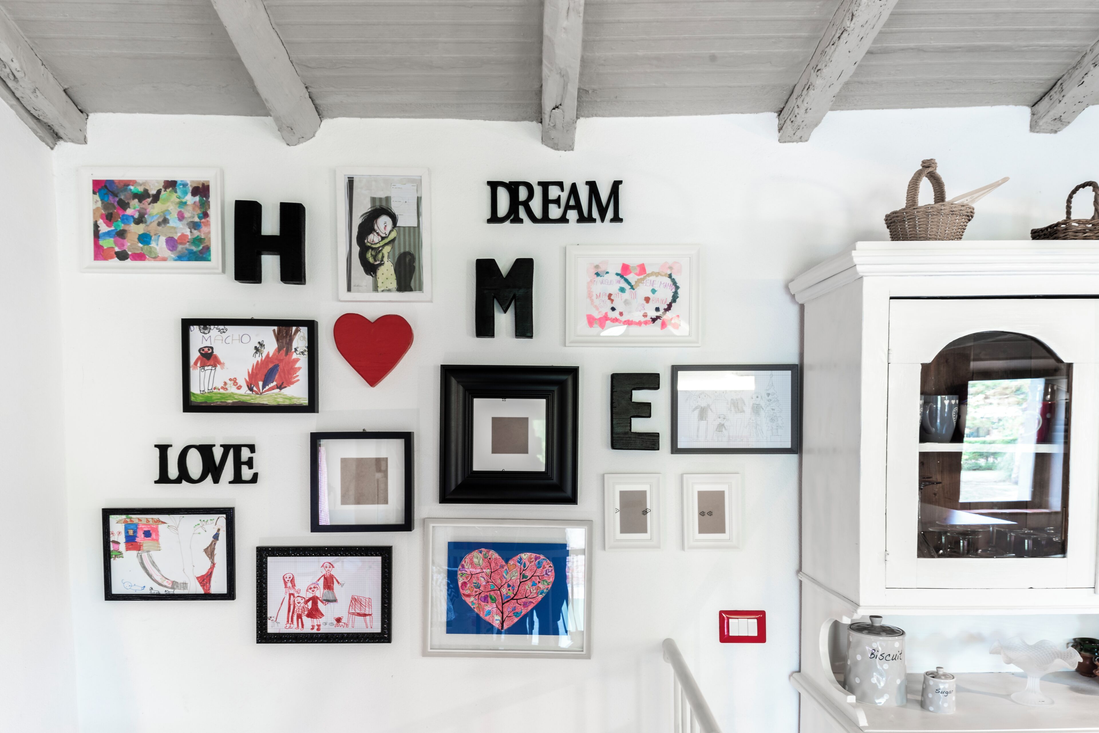 A wall with framed artwork and letters spelling out "HOME" and "LOVE".