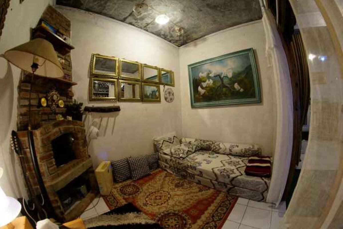 A cozy living room with a fireplace, patterned sofa, and a painting on the wall.