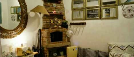 Un accogliente soggiorno con camino in mattoni, un grande specchio e diverse immagini incorniciate appese al muro.