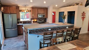 Una cocina moderna con una isla central, electrodomésticos integrados y un comedor con sillas de madera.