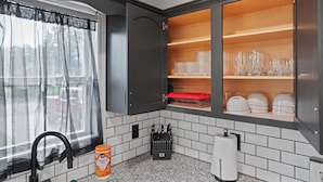 Una cocina con ventana, un lavamanos, una botella de toallitas húmedas y un bloque de cuchillos.