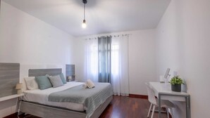 A modern bedroom with a bed, bedside table, and a desk with a chair. - Casa Almada (Ribeira Brava)