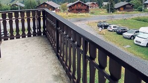 A balcony with a view of a mountain, several wooden cabins, and parked cars. - Praz de Lys resort, duplex apartment 200 metres from the ski lifts (Taninges)