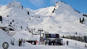 A snow-covered ski resort with a ski lift, a small building, and a mountain backdrop. - Praz de Lys resort, duplex apartment 200 metres from the ski lifts (Taninges)