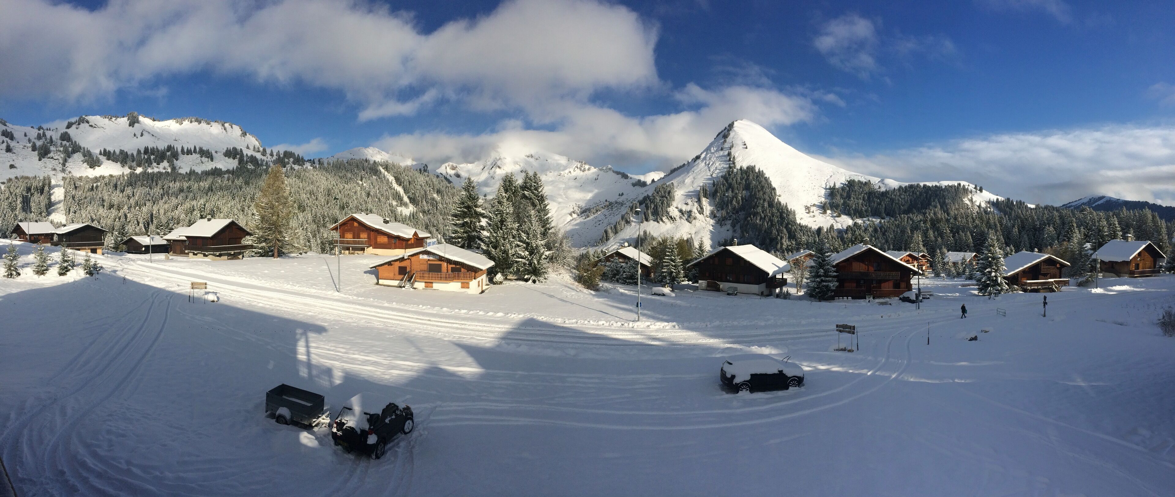 A snow-covered mountain resort with wooden cabins, ski trails, and a clear sky.
