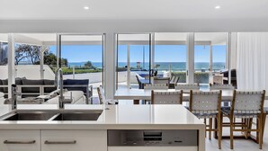 Una cocina moderna con vista al océano, un comedor con sillas y un sofá.