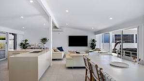 Un espacio habitable moderno con cocina, comedor y un televisor grande.