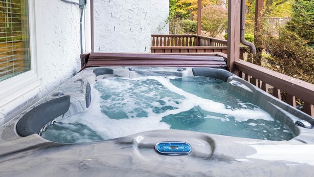 A hot tub with a control panel, surrounded by a wooden deck and a white wall. - Gemutliche Wohnung - hot tub, full kitchen, WiFi (Helen)