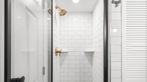 A modern bathroom with white subway tiles, a glass shower enclosure, and a gold showerhead. - Gemutliche Wohnung - hot tub, full kitchen, WiFi (Helen)