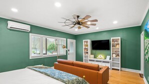 A bedroom with a bed, a brown sofa, a ceiling fan, a TV, and a bookshelf. - Gemutliche Wohnung - hot tub, full kitchen, WiFi (Helen)