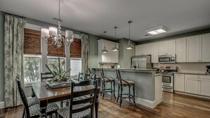A modern kitchen with white cabinets, a central island, and a dining area with a chandelier. - 4 Bedroom Vacation Home Walk to the Beach (North Myrtle Beach)