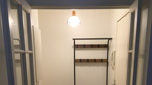A narrow hallway with a wooden herringbone floor, a metal bunk bed, and a hanging light fixture.