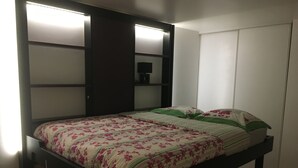 A bed with a floral bedspread, a bedside table, and a wardrobe with a mirror.