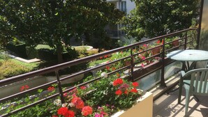 A balcony with a railing, a small table, and chairs.