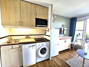 Una cucina compatta con lavatrice, forno a microonde e zona pranzo con vista.