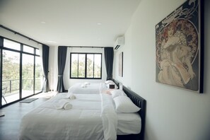 A hotel room with two beds, large windows, and a painting on the wall.