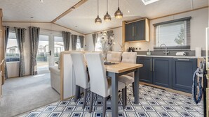 A modern kitchen with a dining area, featuring a skylight, pendant lights, and a patterned floor. - Lodge No 44 | Stewart's Resort Cameron (Cameron)