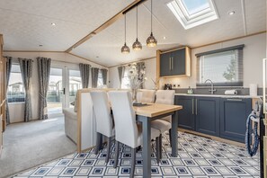 A modern kitchen with a dining area, featuring a skylight, pendant lights, and a patterned floor. - Lodge No 44 | Stewart's Resort Cameron (Cameron)