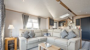 A modern living room with a beige sectional sofa, a wooden coffee table, and a small side table with a lamp. - Lodge No 44 | Stewart's Resort Cameron (Cameron)