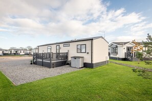 A modern mobile home with a fenced deck, a gravel driveway, and a well-maintained lawn. - Lodge No 44 | Stewart's Resort Cameron (Cameron)