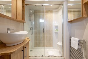 A modern bathroom with a large white sink, a glass-enclosed shower, and a towel rack. - Lodge No 44 | Stewart's Resort Cameron (Cameron)