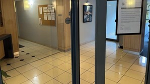 Un hall d’hôtel avec un panneau d’affichage, un comptoir de réception et un avis encadré accroché au mur.