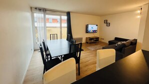 Un salon comprenant un coin repas, un téléviseur et un canapé.