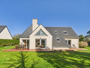 Una moderna casa a due piani con un'ampia veranda, una zona relax all'aperto coperta e un prato curato.