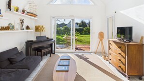 Ein modernes Wohnzimmer mit einem Klavier, einem Fernseher und einem Bücherregal.