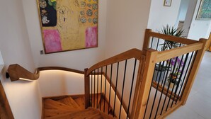 A wooden staircase with a handrail and a metal railing, leading to an upper floor.
