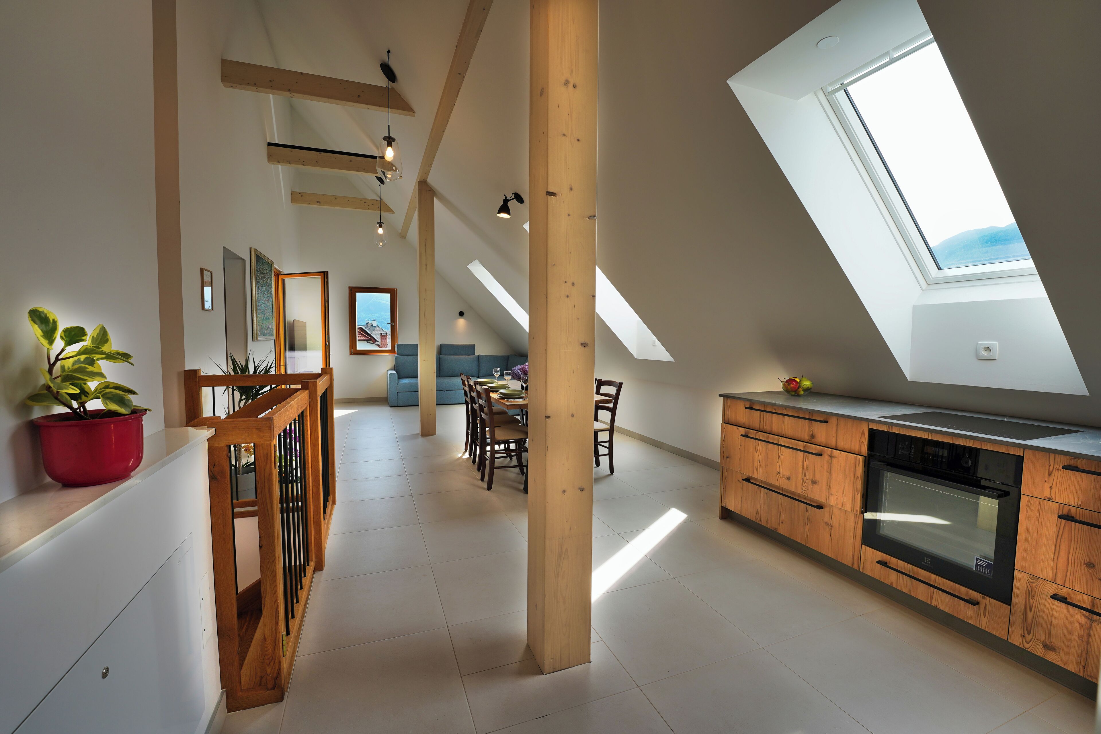 Geräumiges Loft mit hohen Decken, Dachfenstern und einer modernen Küche mit Holzschränken.