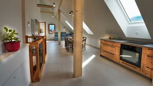 A spacious loft with high ceilings, skylights, and a modern kitchen with wooden cabinetry.