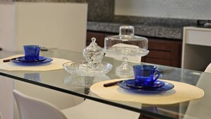 A modern kitchen with a glass dining table, blue glassware, and a decorative glass centerpiece. - Comfort & Beautiful View 300m from Paradise - Wi-Fi/AC (Parnamirim)