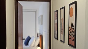A hallway with a bed, a nightstand, and wall art. - Comfort & Beautiful View 300m from Paradise - Wi-Fi/AC (Parnamirim)