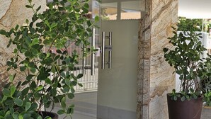 A hotel entrance with a marble facade, a glass door, and two potted plants on either side. - Comfort & Beautiful View 300m from Paradise - Wi-Fi/AC (Parnamirim)