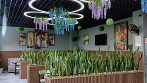 A modern interior with a ceiling grid, hanging plants, and a central planter with long green plants. - Takdiri Homes Executive Studio (Nairobi)
