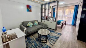 A modern living room with a sofa, coffee table, and a built-in bookshelf. - Takdiri Homes Executive Studio (Nairobi)