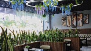 A modern indoor seating area with wooden partitions, hanging plants, and a tiled floor. - Takdiri Homes Executive Studio (Nairobi)