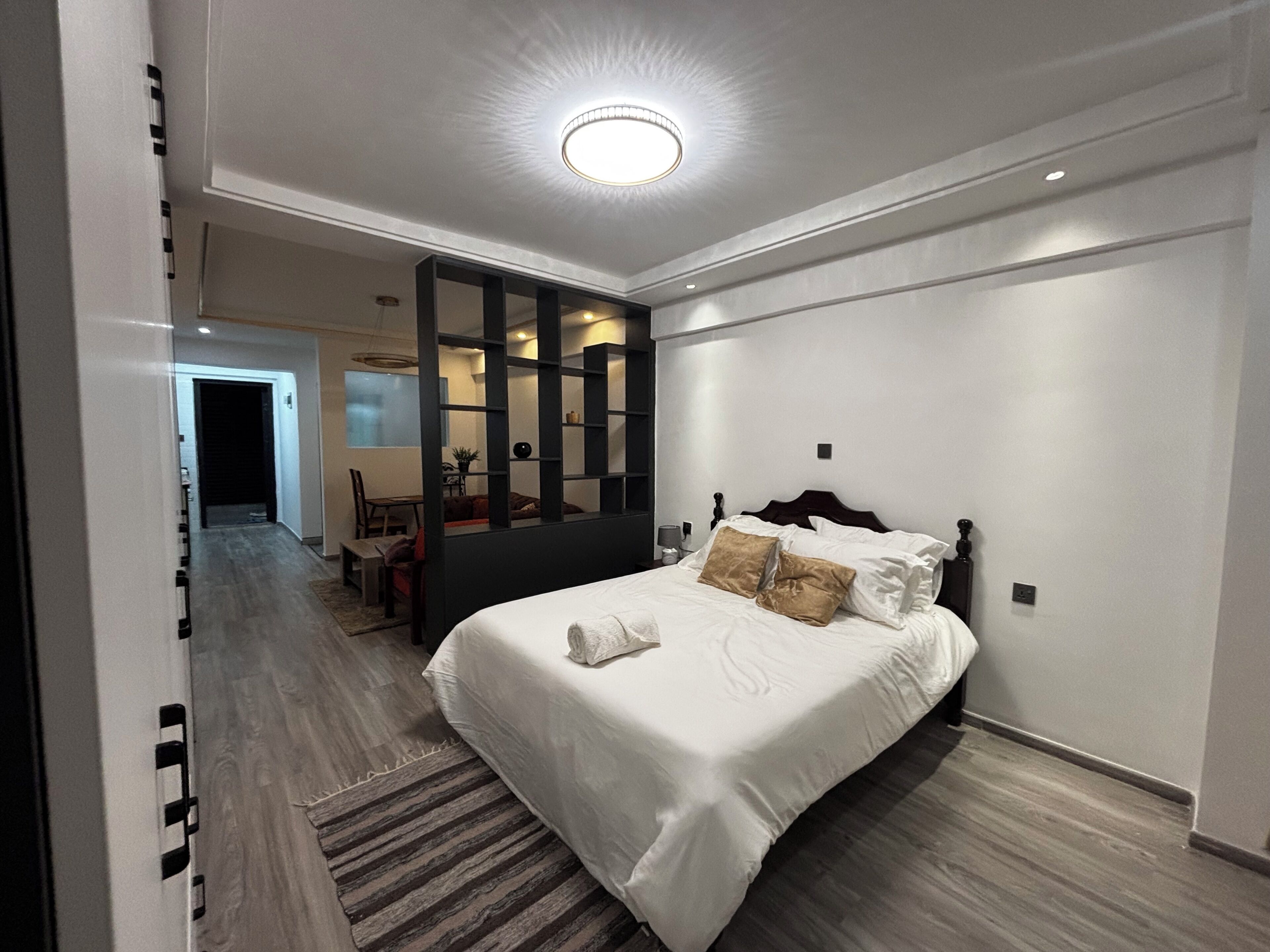 Una habitación de hotel moderna con una cama grande, una zona de estar separada y vistas a otra habitación.