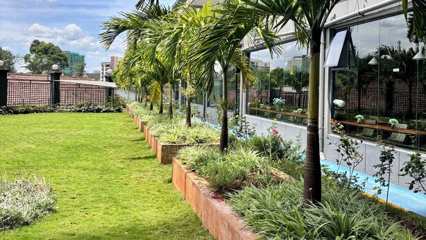 A modern building with a well-maintained garden, including a grassy lawn and various plants. - Takdiri Homes Executive Studio (Nairobi)