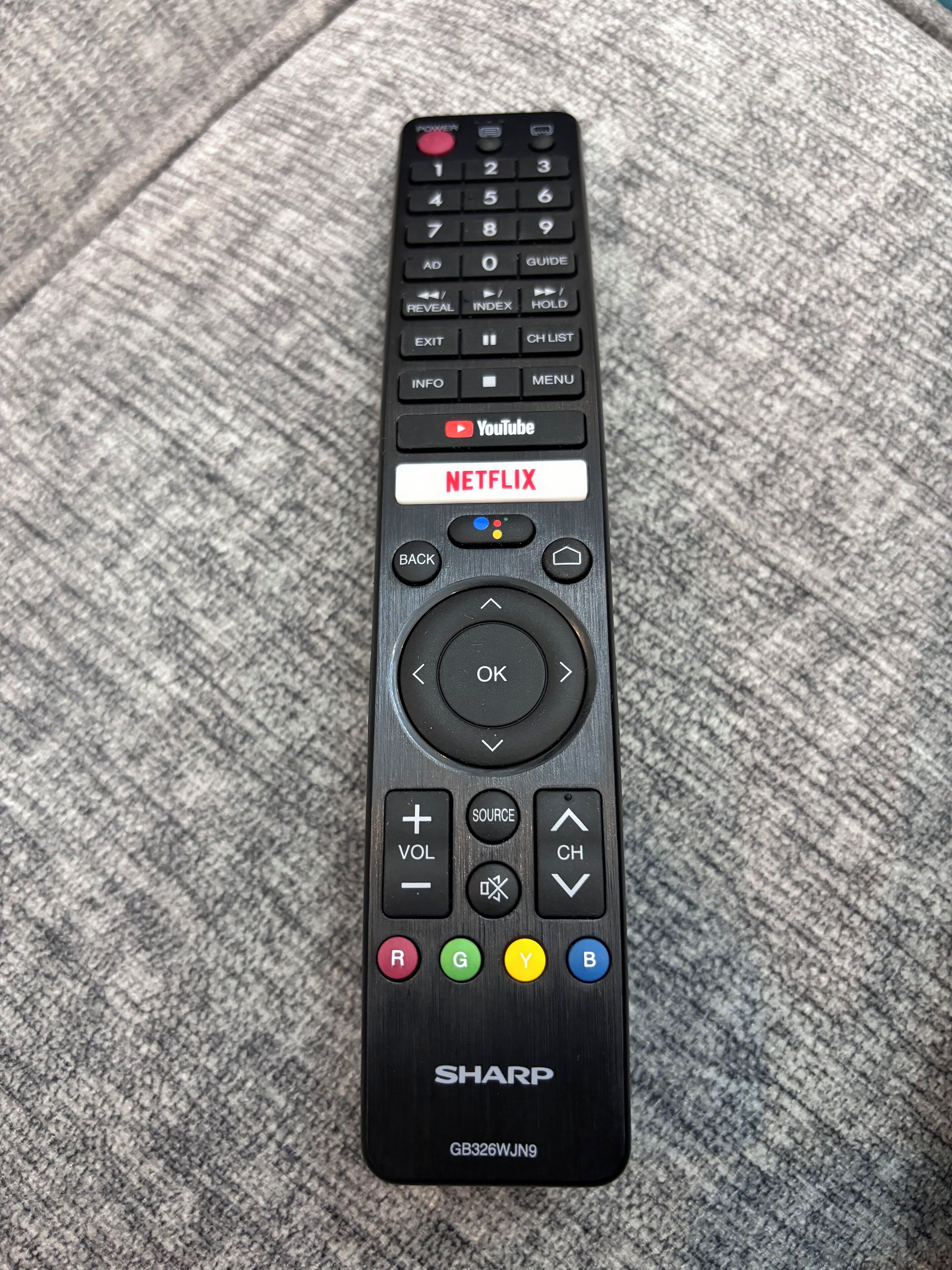 A black Sharp remote control with a Netflix button, volume and channel buttons, and directional keys.