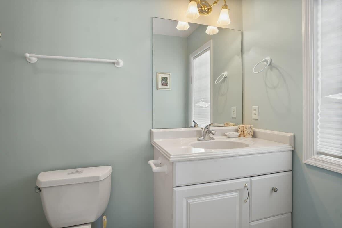 A bathroom with a white toilet, a sink with a mirror above it, and a towel rack.