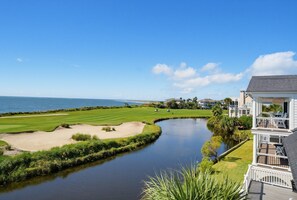 A golf course with a water feature, a view of the ocean, and a residential building with a balcony. - Best Views on the Island - Resort Access Included (Fripp Island)