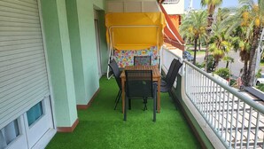A balcony with artificial grass, a table, chairs, and a yellow canopy. - SALOU FAMILY APARTMENT (Salou)