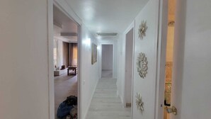 A hallway with white walls, a door on the right, and a bench in the left room. - SALOU FAMILY APARTMENT (Salou)