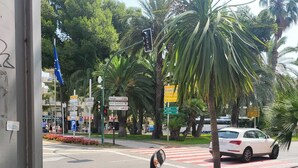 A scooter parked at a street corner with palm trees and a traffic light in the background. - SALOU FAMILY APARTMENT (Salou)
