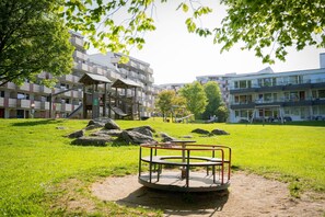 Relax in a serene outdoor space surrounded by lush greenery and a playground for the kids.