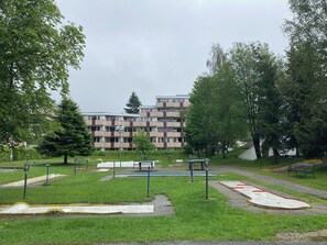 Stroll through the serene park area, featuring a well-maintained lawn, benches, and a playground for kids, surrounded by lush greenery.