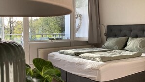 Une chambre avec un lit, une fenêtre avec des rideaux, un radiateur et une plante.